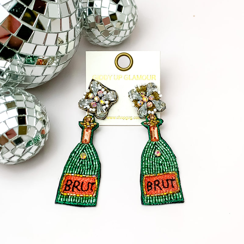 Bottles of Brut Beaded and Jeweled Earrings. Pictured on a white background with disco balls in the top left corner.