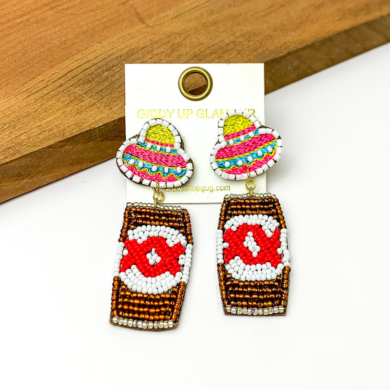 Beaded Gold Beer Can Earrings with Sombrero Studs. Pictured on a white background with a wood piece at the top.