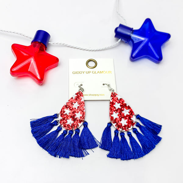 USA Red Sparkly Teardrop Earrings With Blue Tassels. Pictured on a white background with a red and blue star above the earrings.