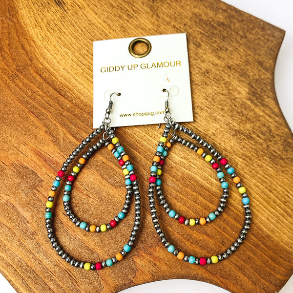Beaded Open Double Drop Earrings in Silver Tone and Multicolor. Pictured on a piece of wood.