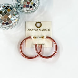 Light Up Medium Neon Hoop Earrings In Light Pink. Pictured on a white background with disco balls in the top left corner.