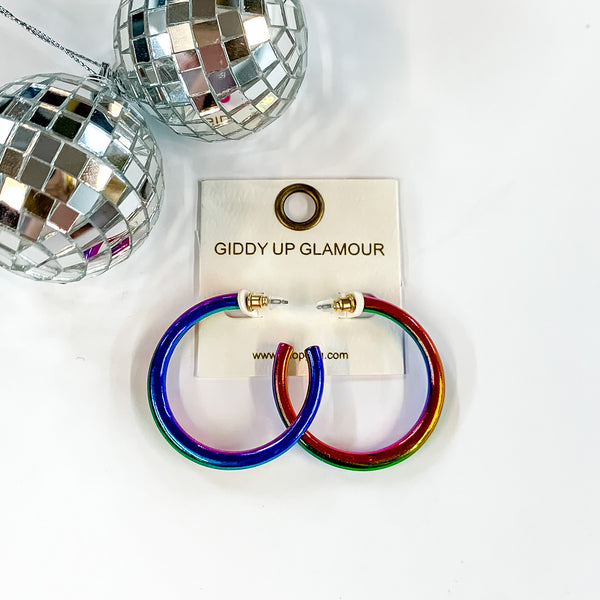Light Up Medium Neon Hoop Earrings In Multicolored. Pictured on a white background with a disco ball in the top left corner.