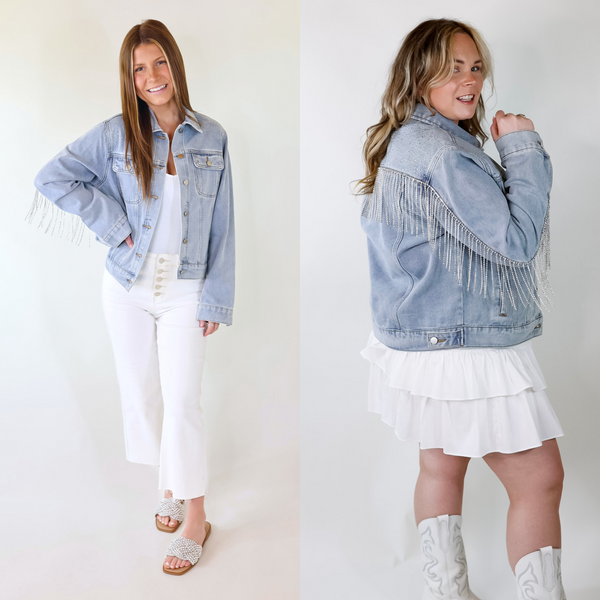 Model is wearing a light wash denim jacket featuring crystals near the shoulders, a crystal fringe on the back, pockets, collar, and button up front.
