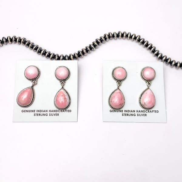 In the picture are Navajo pink conch teardrop earrings with a white background.