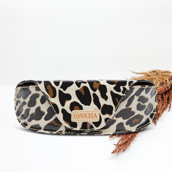 Sunglass case in a leopard print and light tan Consuela patch on the front. This tote is pictured in front of pompous grass on a white background.