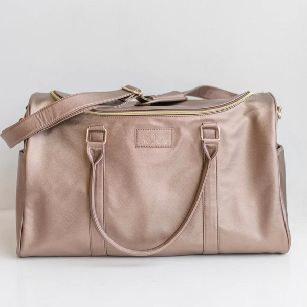 Metallic mocha duffel bag with hot pink handles. This bag has a gold top zipper and pocket on each side. This bag is pictured on a light grey background. 