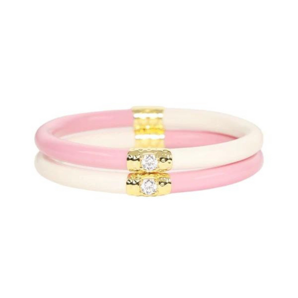 Two half white and half pink plastic, tube bracelet with two gold segments on the bracelet. These bracelets are pictured on top of each other on a white background. 