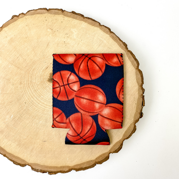 Basketball print koozie with black background. This koozie is pictured on a piece of wood on a white background.