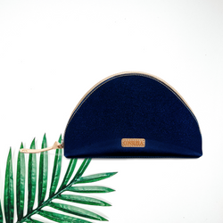 In the center of the picture is a dome shaped bag in a sparkly blue color. To the right of the bag is a palm leaf, all on a white background. 