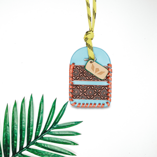 Centered in the picture is a luggage tag in blue and orange. To the right of the luggage tag is a palm leaf, all on a white background.