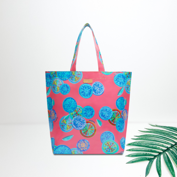 A large size pink bag with a colorful fruit pattern. Pictured on white background with a palm leaf.