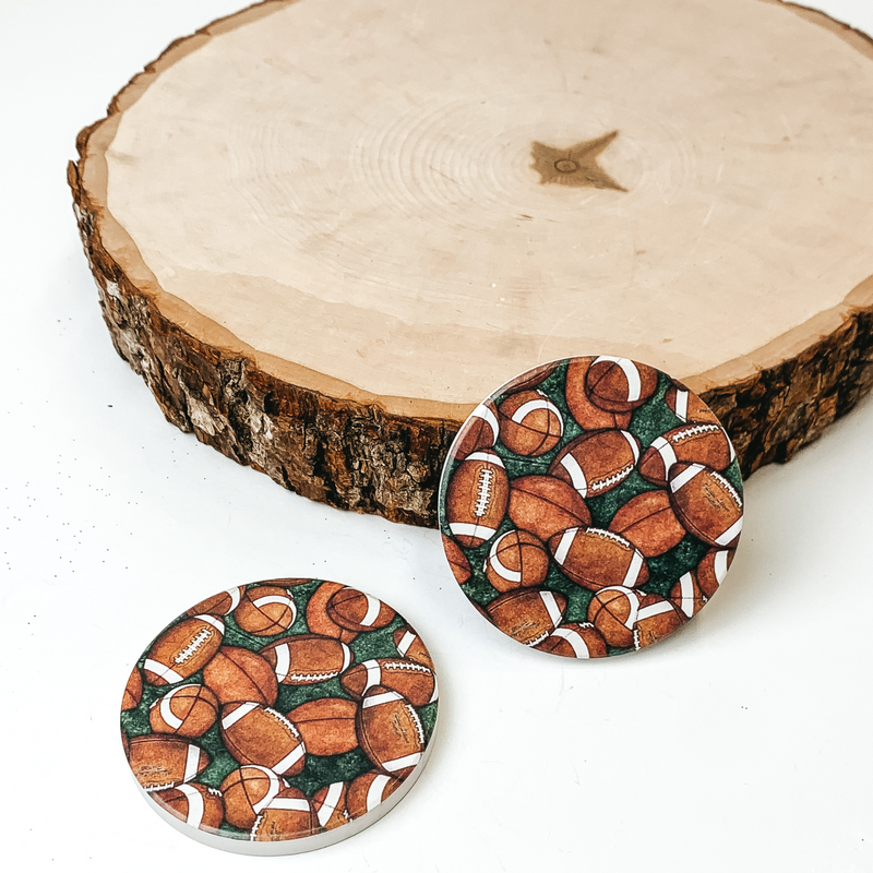 Set of two football car coasters pictured on a piece of wood, with a white background. 