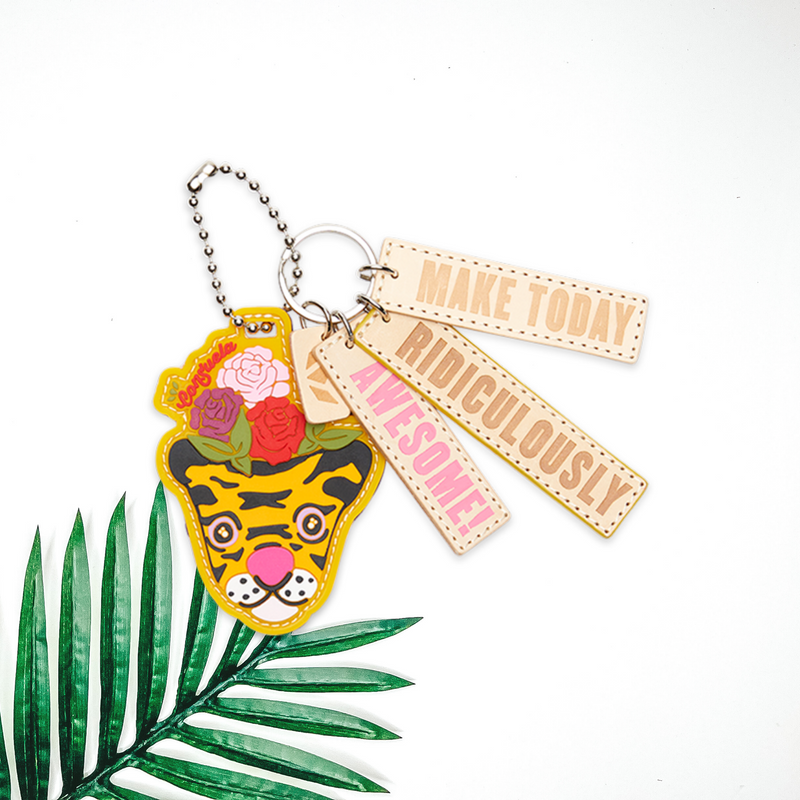 In the center of the picture is a tiger bag charm in yellow, with three other charms attached that says, "make today", "ridiculously", and "awesome". Background is solid white. 