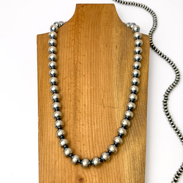 Centered in the picture is a large strand of navajo pearls on a wooden backdrop.