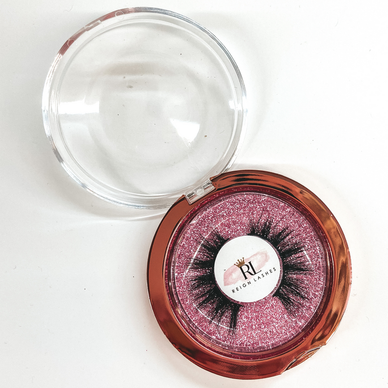 Round Glitter casing with black false eyelashes. Pictured on white background.