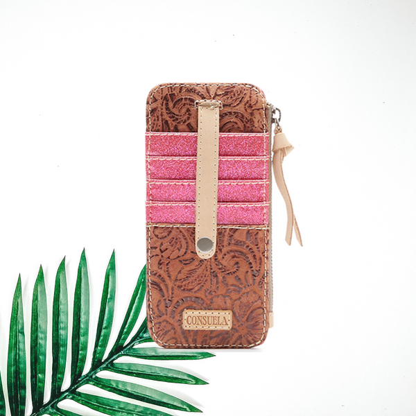 Centered in the picture is a card organizer in a brown tooled leather color with pink accents. To the right of the organizer is a palm left, all on a white background.