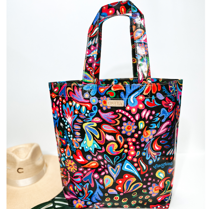 A large size black bag with multi color designs. Pictured on white background with a palm leaf and straw hat.