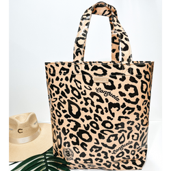 A large size leopard print bag with handles. Pictured on white background with palm leaf and straw hat.