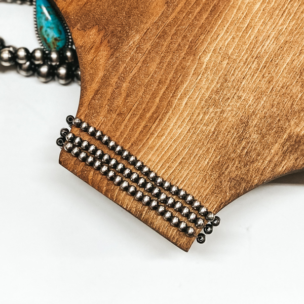 Three 4mm navajo pearl stretchy bracelets places around a wooden slat. Pictured on white background with sterling silver and turquoise pieces.