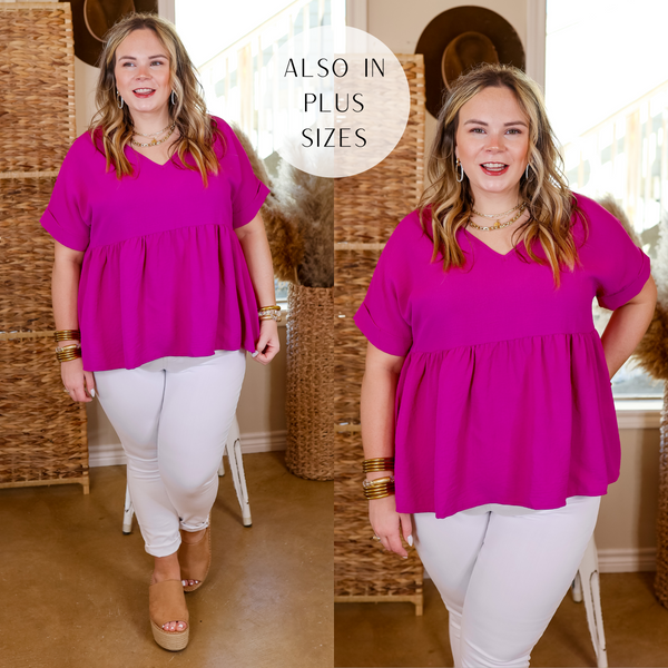 Model is wearing a short sleeve, v neck, babydoll top in magenta. Model has this top paired with white jeans, nude espadrilles and gold jewelry. 