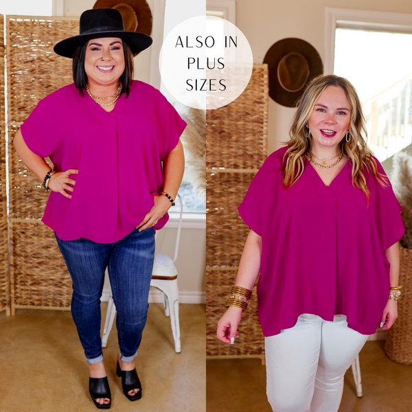 Model is wearing a short sleeve v neck top in magenta. Model has this top paired with black heels, gold jewelry and a black hat. 