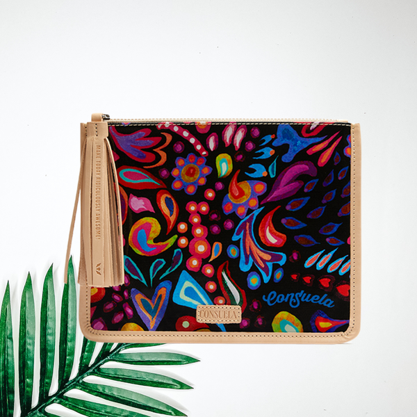 A black pouch with a multi color paisley print. Pictured on white background with a palm leaf.