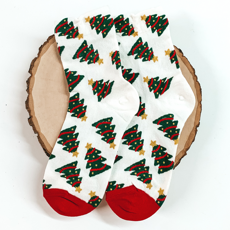 White ankle socks with red toes and a christmas tree design. These socks are pictured on a piece of wood on a white background. 