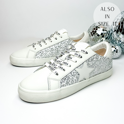 White tennis shoes with a white pearl and clear crystal design over the side of the shoe and the heel. These shoes also have a white star emblem on the side of the shoe. These shoes are pictured on a white background with disco balls behind them on the right hand side.
