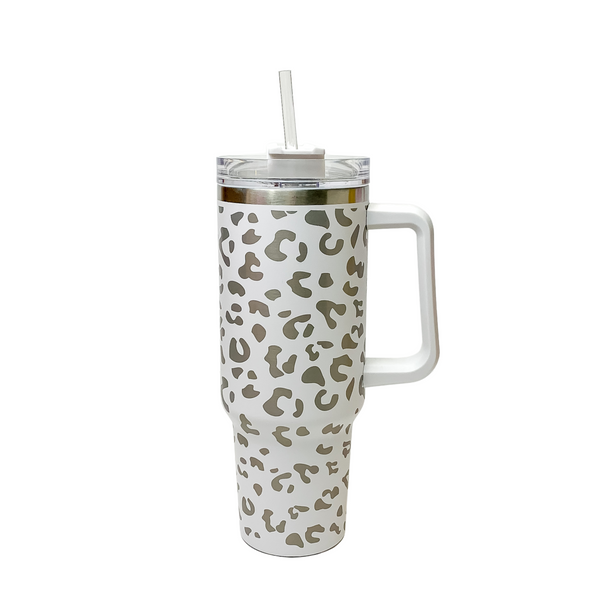 Pictured is a white tumbler with a handle, clear straw, and a leopard print design. This tumbler is pictured on a white background. 