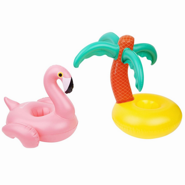 On the left there is an inflatable, pink flamingo drink holder. On the right there is a palm tree on a beach inflatable drink holder. These drink holders are pictured on a white background. 