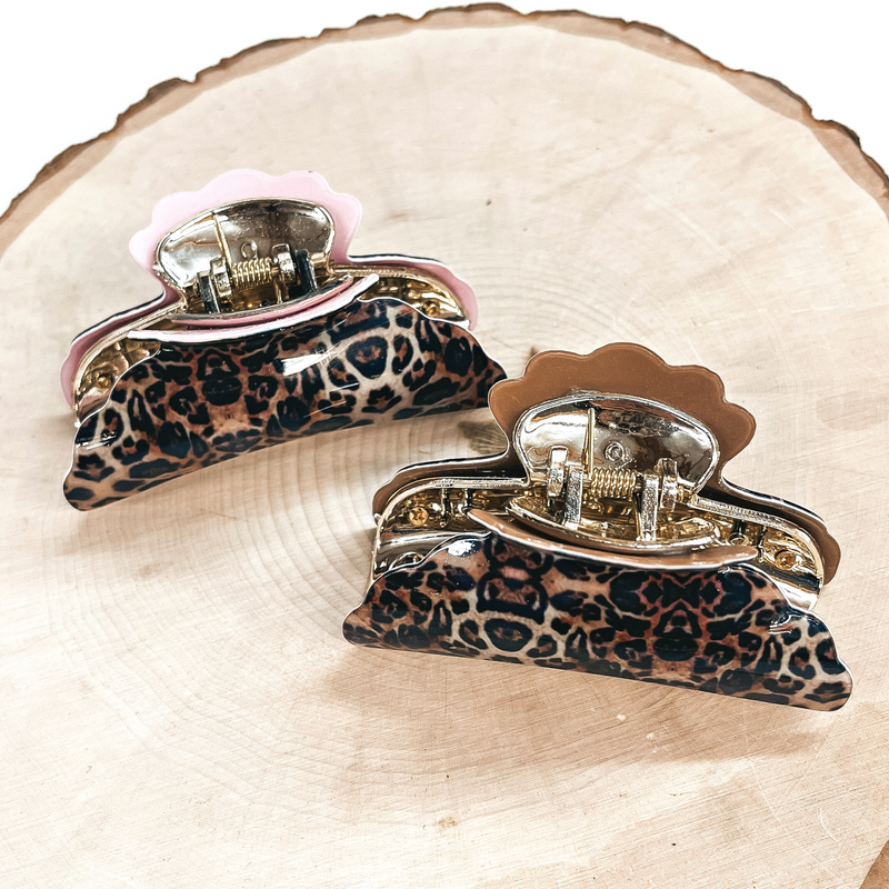 These are small leopard print hair clips with a gold tone inlay in light pink and light  brown.   Both of these hair clip are taken on a slab of wood and on a white background.