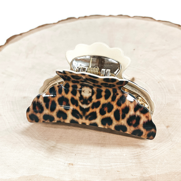 This is a yellow leopard print hair clip with a gold tone inlay in ivory.   This hair clip is taken on a slab of wood and on a white background.