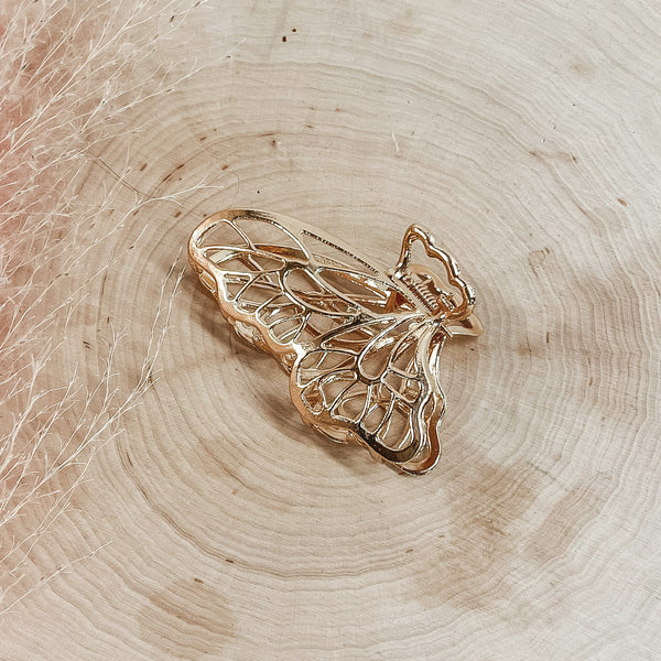Gold butterfly hair clip pictured on a piece of wood. 