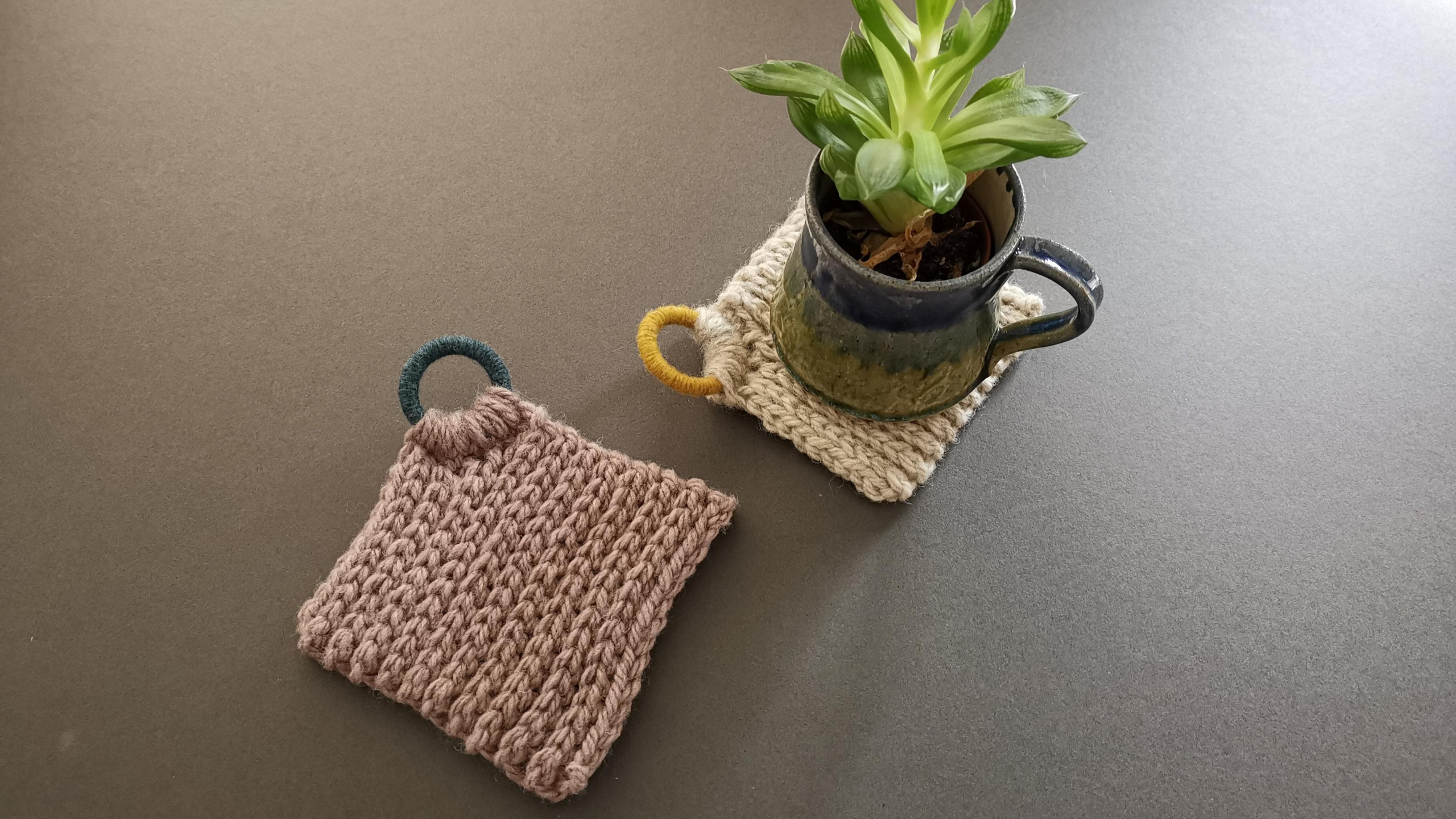 Grey background with two coasters in netutral colours.  One has a small mug and a succulent on it.
