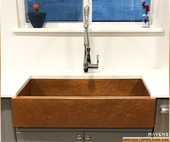 Hammered copper farm sink image installed in kitchen with light countertops 
