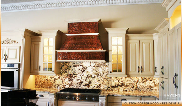Hammered copper kitchen hood with stone backsplash in residential kitchen, built and installed by Havens.