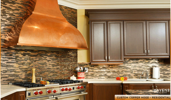 Beautiful and prominent copper kitchen hood installed with dark cabinetry.