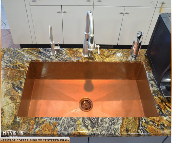 Custom copper sink with a center drain on a luxury kitchen's island.