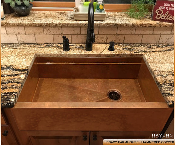 Hammered copper farm style sink with an apron front and built in ledge, designed and built in the USA.