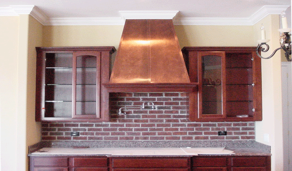 Polished copper range hood installed in kitchen.