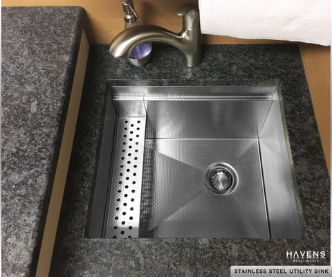 Custom utility stainless steel sink with a built in ledge and textured finish, installed under quartz counters.