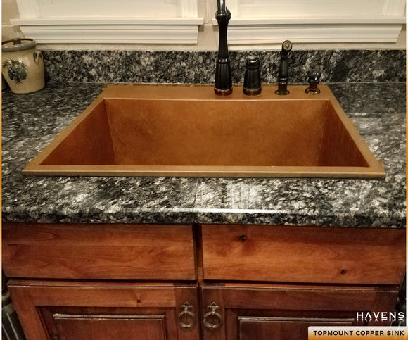 Heritage copper sink with granite countertops and a rear deck for integrated faucets.