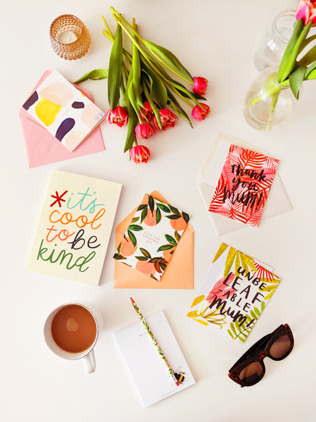 mother's day cards scattered across a table surrounded buy stationery and a cup of coffee