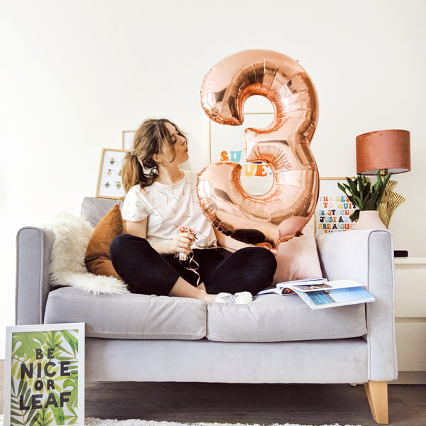 3rd biz birthday - annie sitting on a sofa with a big "3" balloon!