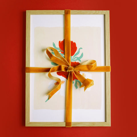 a framed print, tied with velvet ribbon on a red background