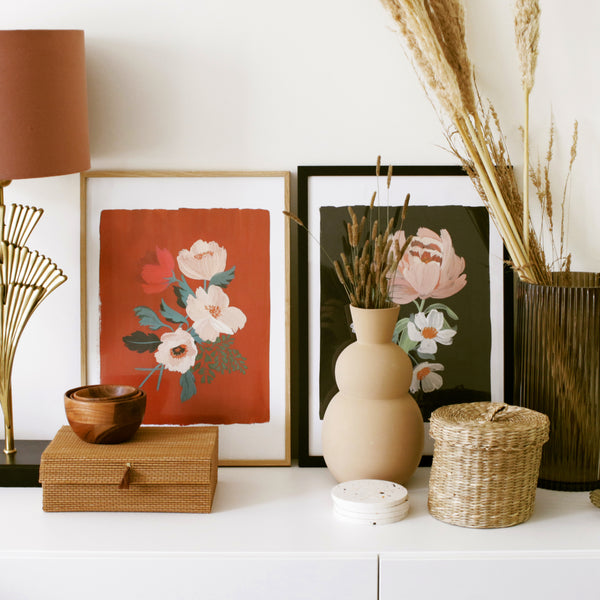 A side cabinet decorated with moody-hued floral prints and wicker and rattan storage boxes
