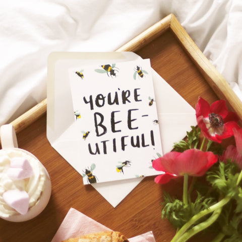 You're Bee-utiful Card, resting on a breakfast in bed tray surrounded by frothy coffee and flowers 