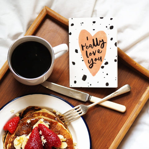 a Valentine's card with coffee and pancakes, in bed