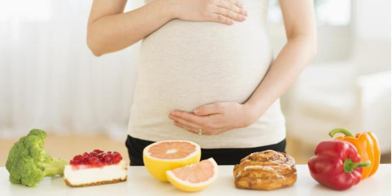 pregnant woman behind table with fruit and vegetables