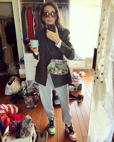 Clare Vivier Taking A Selfie In Front of A Mirror, Wearing Grey Sweatpants, Different Colored Sneakers, Dark Blazer and our Strawberry Snake Sissy As A Crossbody Bag